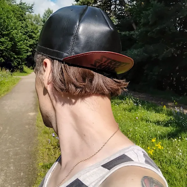 Person strolling through a city park path in a dark leather cycling cap – styled for walking commuters.