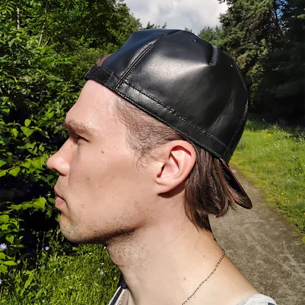Man wearing an adjustable leather cycling cap while walking casually in a city park.