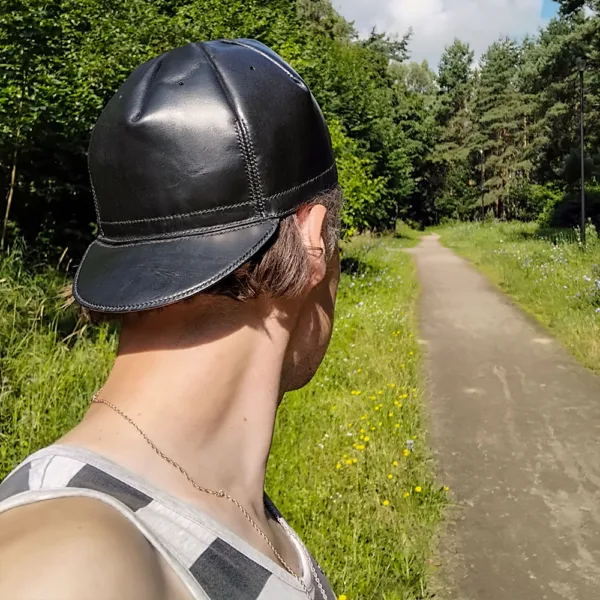 Close-up of leather cycling cap worn in a natural park setting, styled with everyday streetwear.